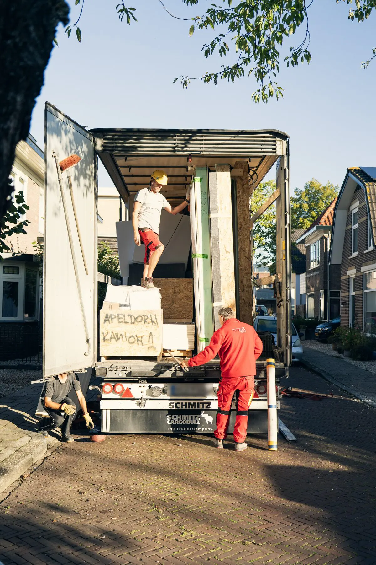 Vrachtwagen met prefab wanden in een straat in Apeldoorn, met een kist waarop Apeldoorn staat
