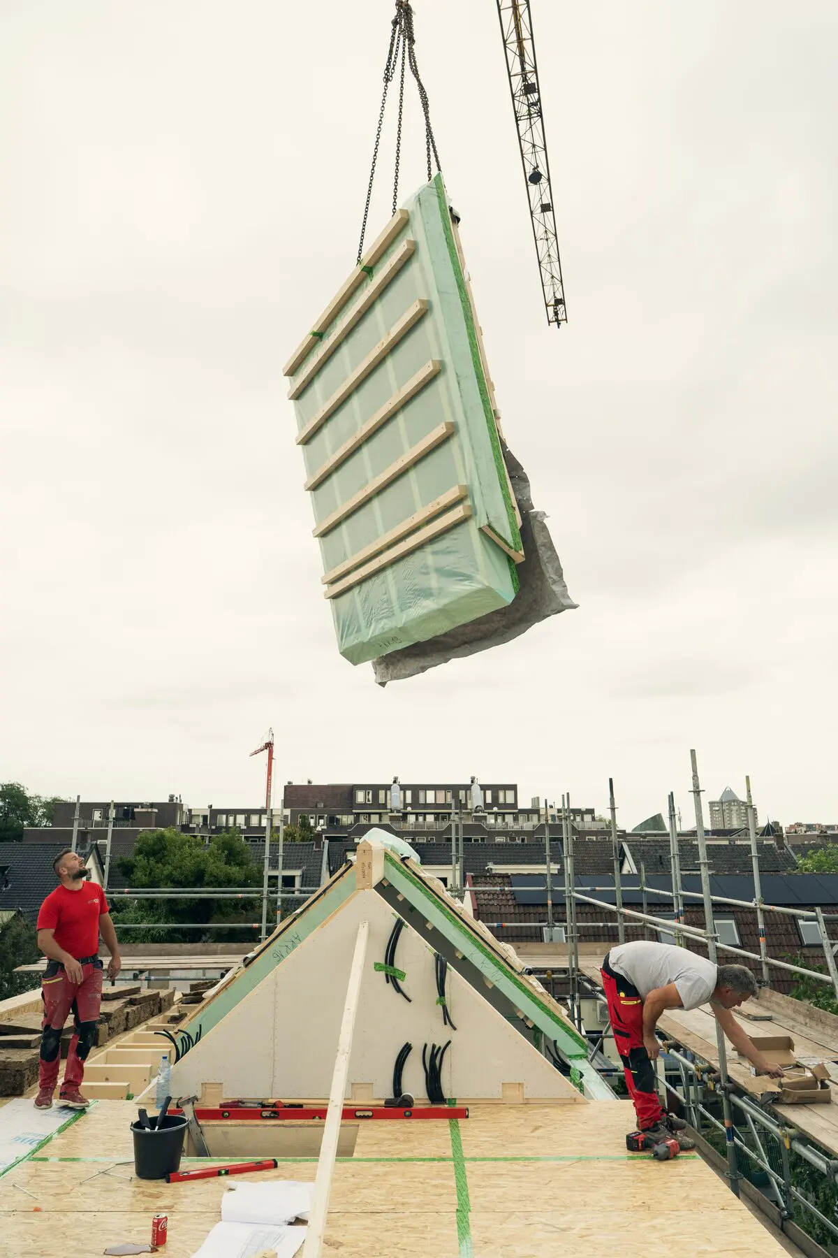 Een dakelement hangt aan de kraan boven de ploeg op de verdieping