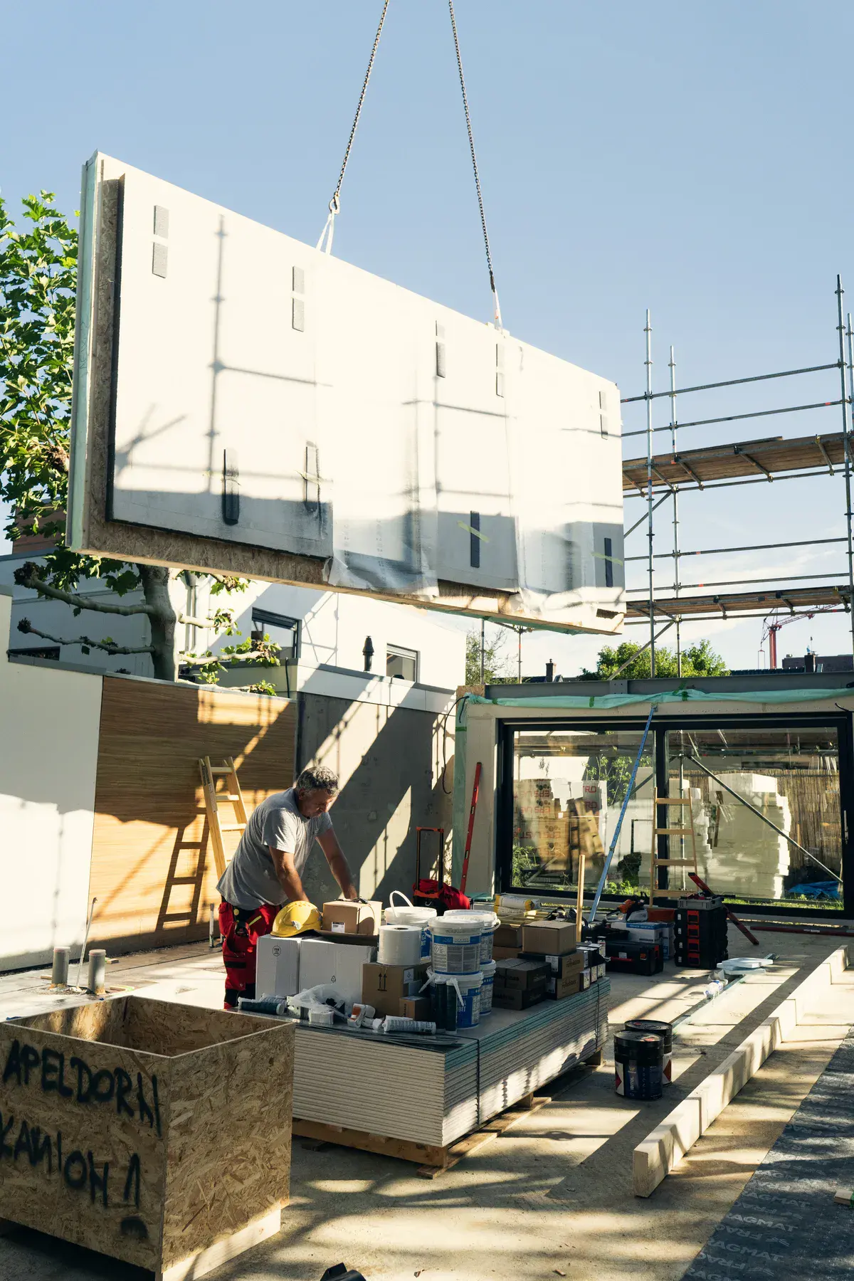 Een prefab gevelpaneel wordt met een hijskraan op zijn plek gehesen bij een woning in aanbouw