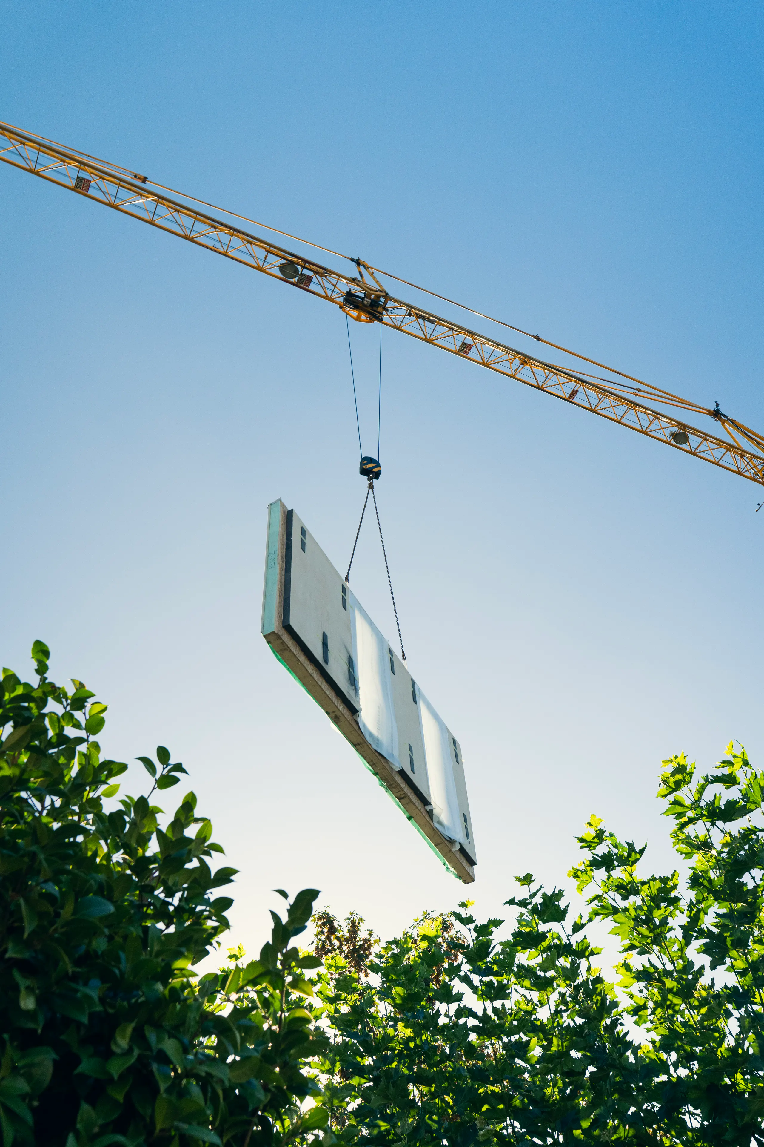 Prefab wandelement wordt met een bouwkraan op zijn plaats gehesen