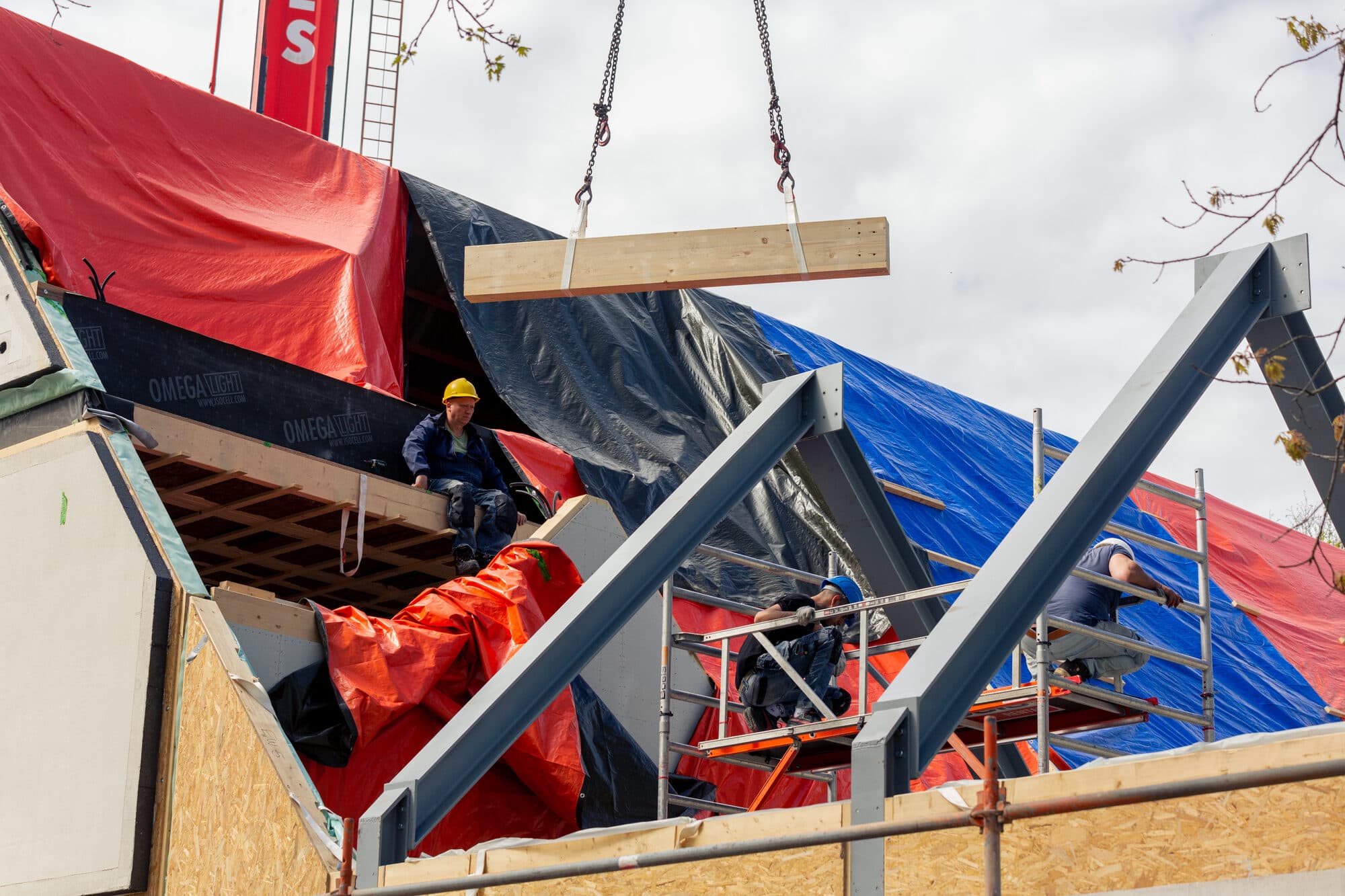 De kraan hijst een prefab wandelement op zijn plaats tijdens de montage
