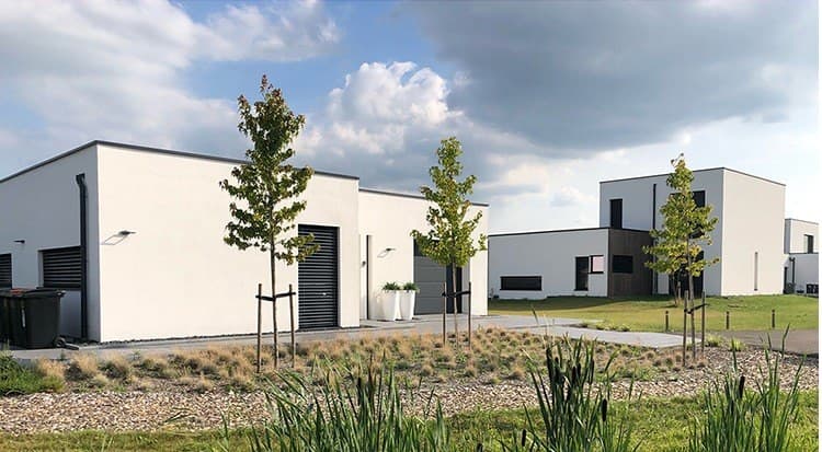 Rij witte woningen met platte daken langs een groene berm