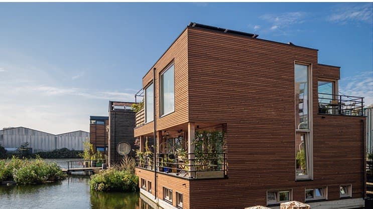 Woonarken met houten gevels aan het water, met vlonders en balkons