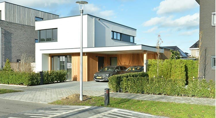 Woning met witte gevel, houten inbouwcarport en een auto op de oprit