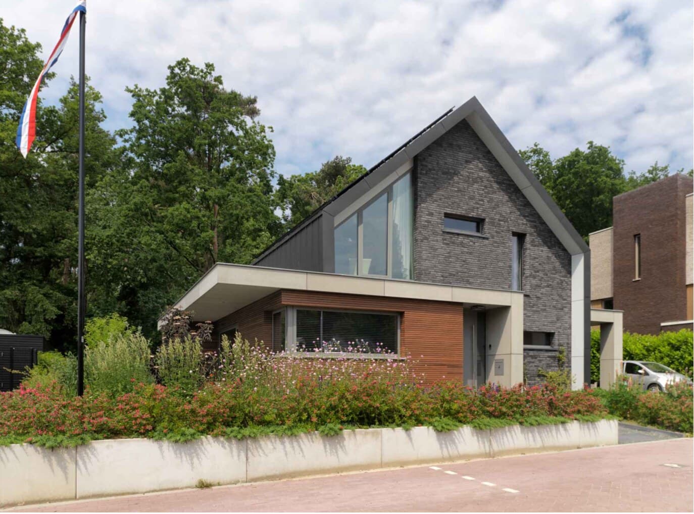 Afgewerkte woning met een hoge kap en Nederlandse vlag