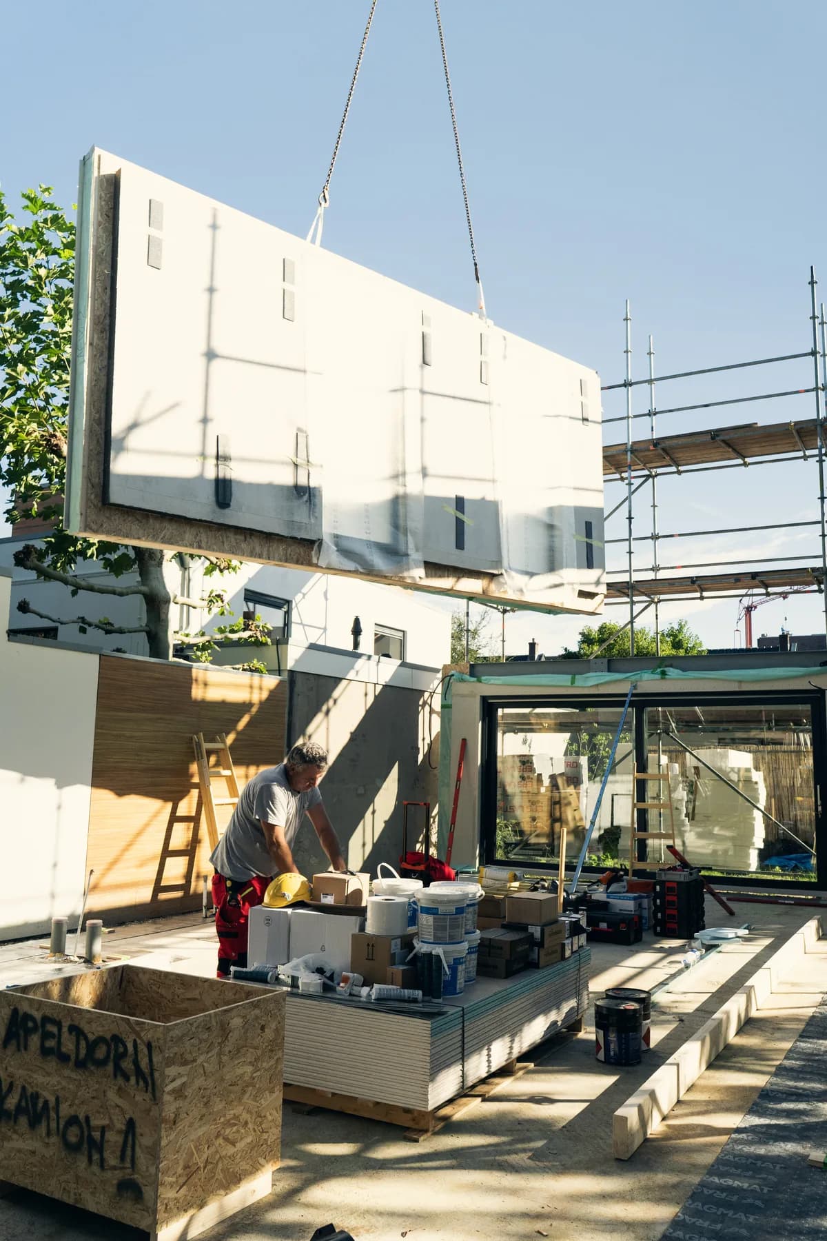 Een prefab gevelpaneel wordt met een hijskraan op zijn plek gehesen bij een woning in aanbouw